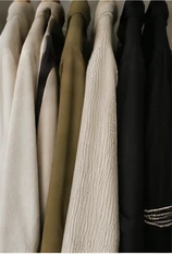 A rail of softly textured clothes in neutral shades